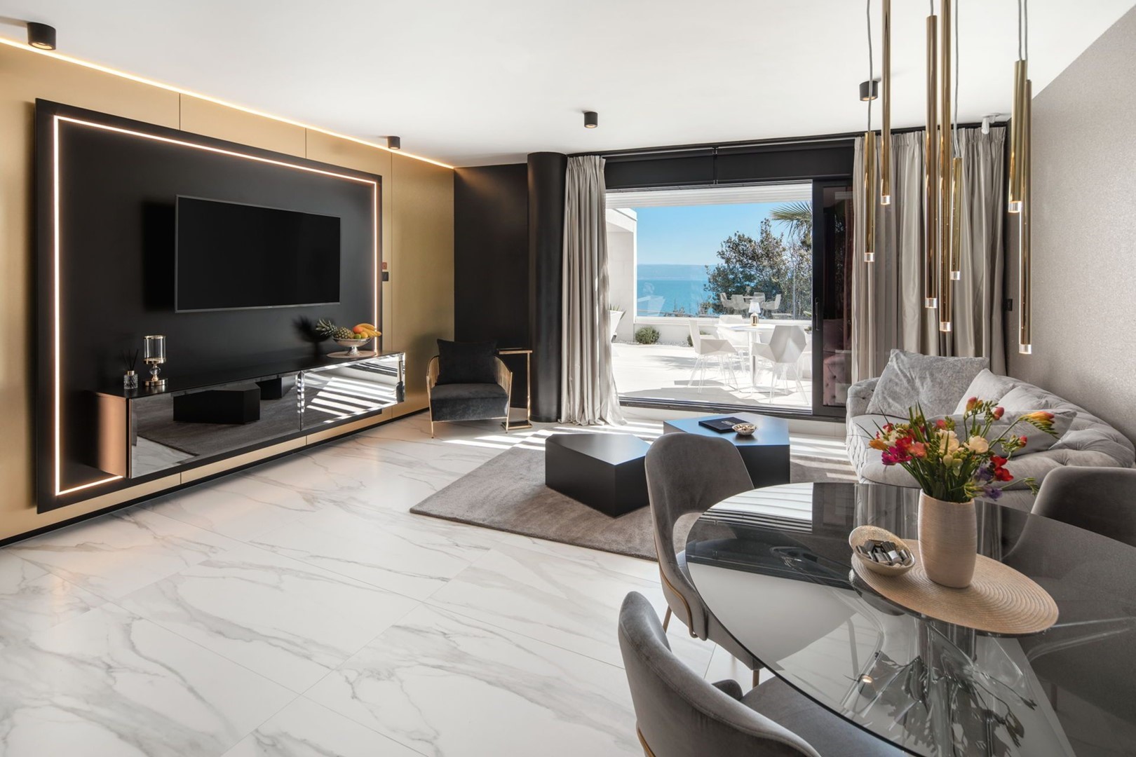 Ein modernes Wohnzimmer einer Luxuswohnung zur Miete mit einem bequemen Sofa, einem Couchtisch, einem LCD-Fernseher und einem eigenen Ausgang zur Terrasse