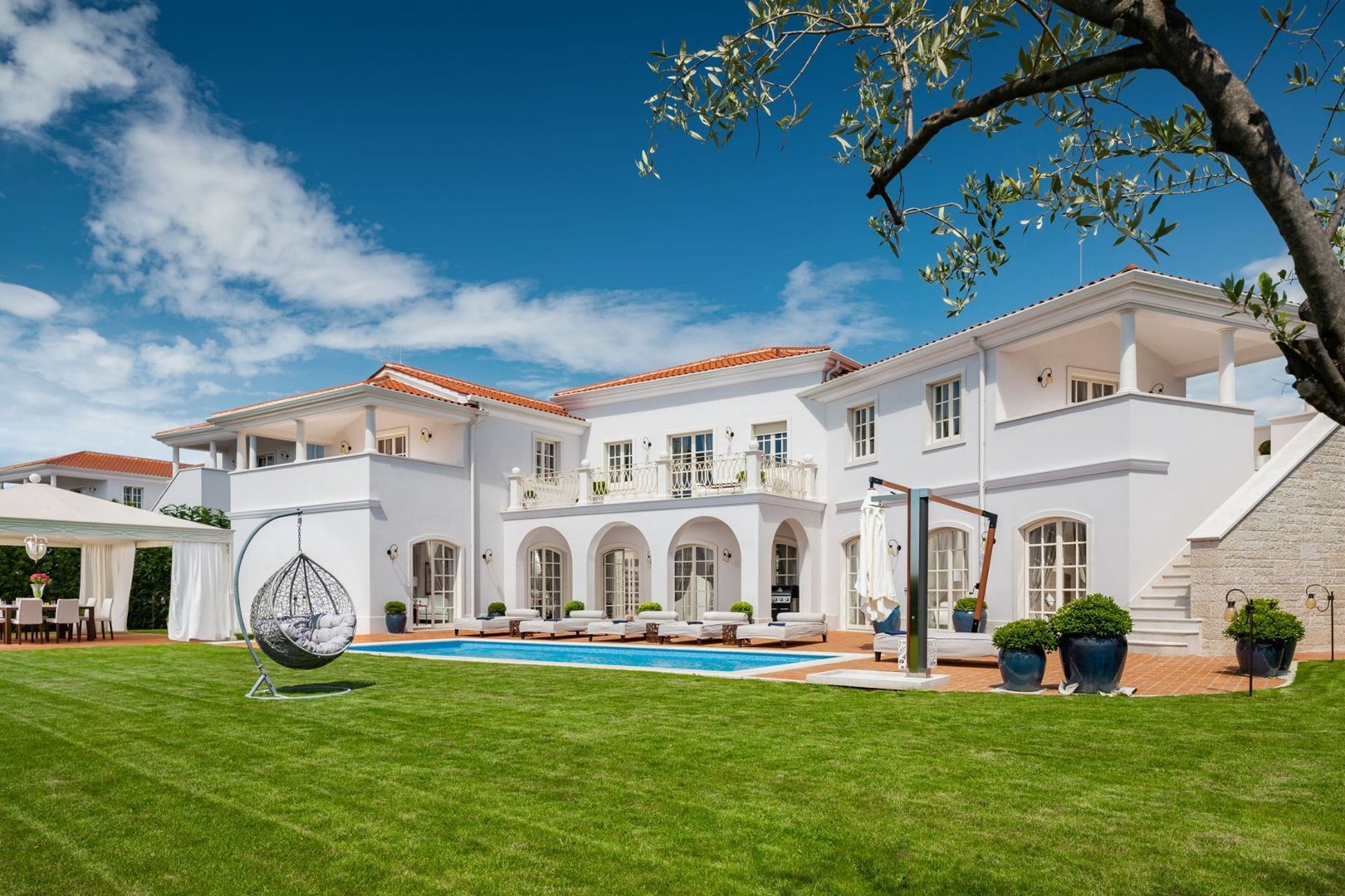 A view of the luxurious villa Ivana with a private pool, a landscaped green lawn with a garden swing and an outdoor terrace