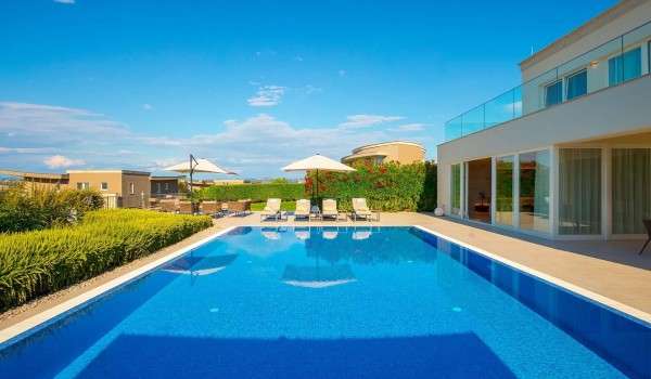 View of the large heated pool surrounded by sun loungers on the private paved terrace in the fenced yard of the luxury villa Residenzia Imperiale in Savudrija in Istria