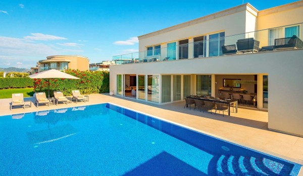 View of the large heated pool surrounded by sun loungers and parasols on the paved terrace in front of the family holiday villa Residenzia Imperiale in Istria