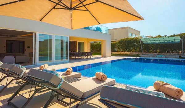 Parasol above sun loungers next to a large private pool in front of the family villa for rent Residenzia Imperiale in Istria