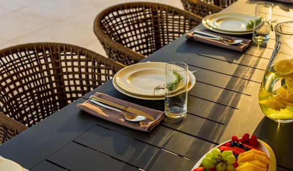 Fruits and dishes served on the outdoor dining table with chairs on the roofed patio in front of the villa Residenzia Imperiale