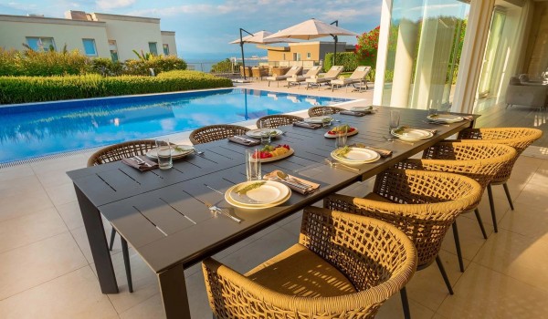 Large outdoor dining table with chairs in the roofed part of the private paved terrace of the luxury villa Residenzia Imperiale in Savudrija