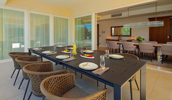 View of the interior of the ground floor of villa Residenzia Imperiale from the roofed part of the outdoor terrace with a dining table and chairs