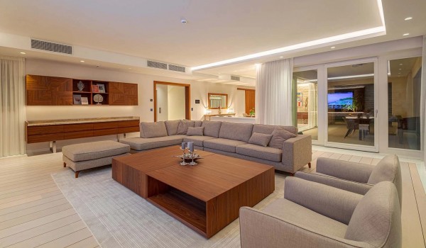 Interior of the spacious living room with a large corner sofa, two armchairs, a modern wooden table and an LCD TV on the ground floor of a holiday villa in Istria