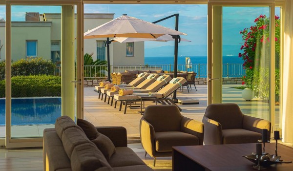 View of the sunny terrace with pool surrounded by sun loungers from the comfortable corner couch in the living room of the luxury villa Residenzia Imperiale in Savudrija