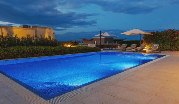 Large private heated pool surrounded by sun loungers with parasols on the paved, fenced terrace of the modern villa Residenzia Imperiale in Savudrija