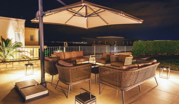 Outdoor seating with a parasol on the paved private terrace with heated pool in front of the luxury villa Residenzia Imperiale in Istria