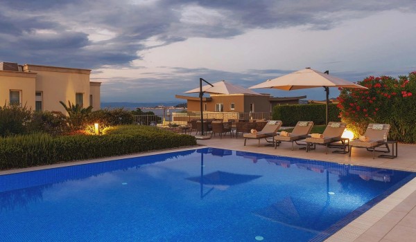 Illuminated heated pool with sun loungers and parasols on the fenced terrace of the luxury villa Residenzia Imperiale for rent and vacation in Istria