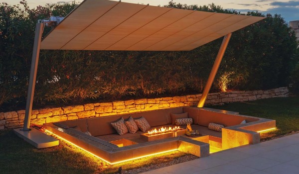 A lit outdoor stone fireplace surrounded by a sitting area in the fenced yard of the family villa for rent Residenzia Imperiale in western Istria