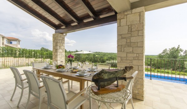 Dining area on roofed terrace in luxury pet-friendly villa in Višnjan for family vacation and rent.