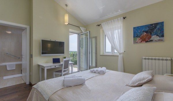 King-size bed in bedroom of luxury pet-friendly villa in Višnjan for vacation and rent.