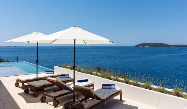 Sunbathing area near private pool in luxury Dalmatian villa Crystal Palace by the sea with parasols.