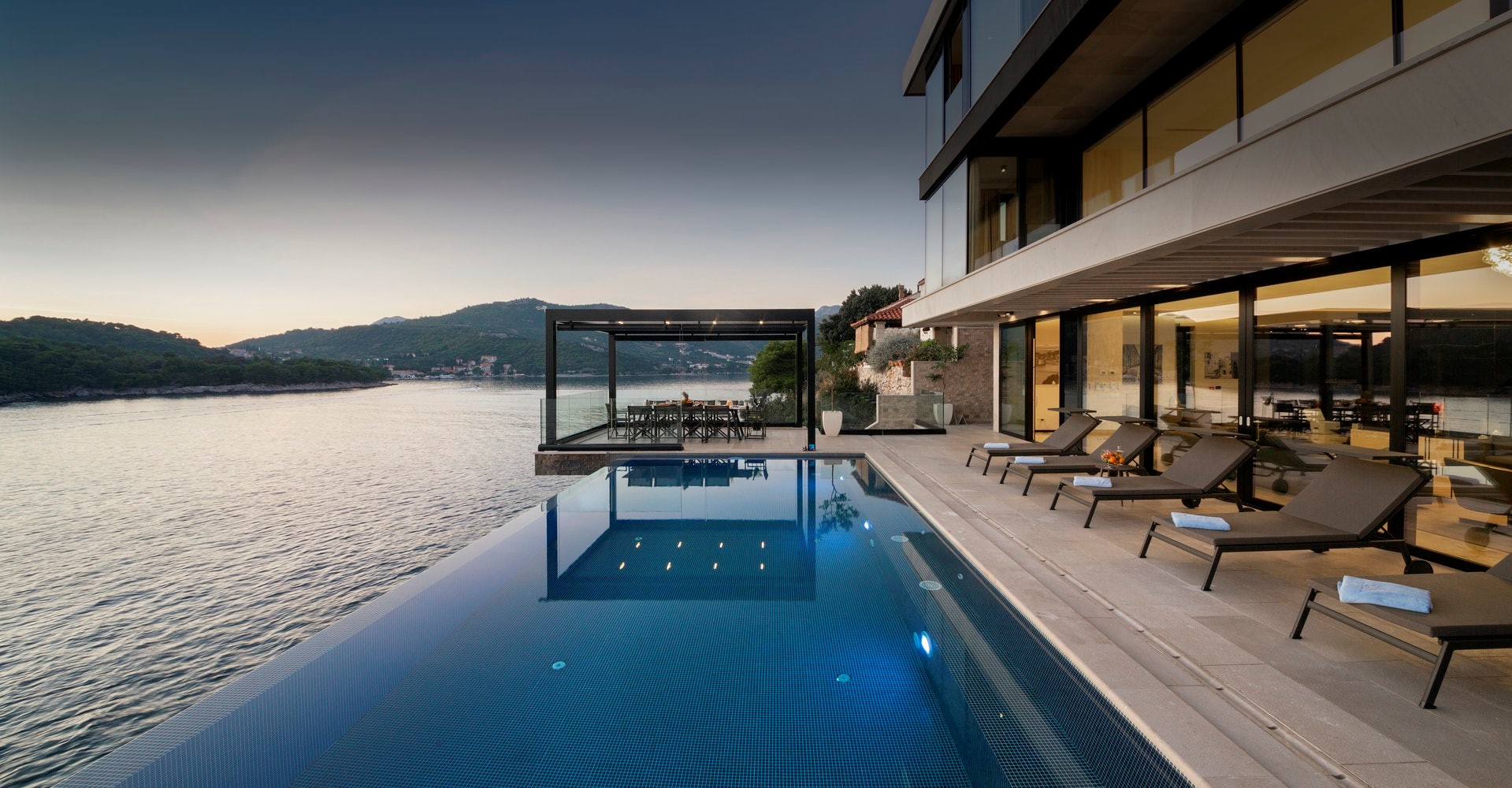 Ležaljke oko privatnog bazena luksuzne obiteljske vile u Hrvatskoj s concierge uslugom i pogledom na more u Dubrovniku