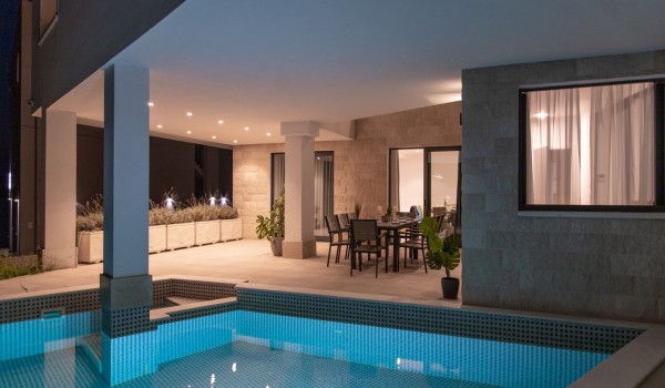 Night view of a private pool and dining table on the terrace in a Croatia luxury sea view villa with gym and sauna in Trogir