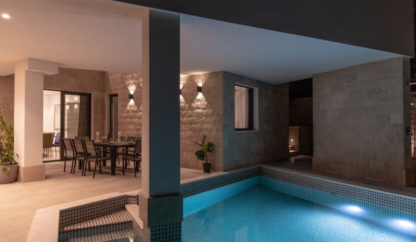 Night view of a private pool and dining table on the terrace in a Croatia luxury sea view villa with gym and sauna in Trogir