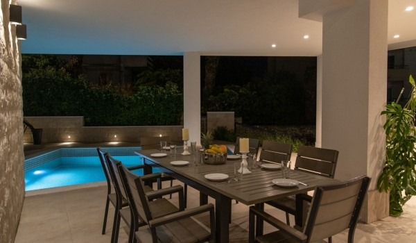Night view of a private pool and dining table on the terrace in a Croatia luxury sea view villa with gym and sauna in Trogir