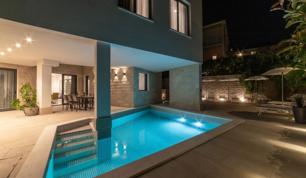 Night view of a private pool and dining table on the terrace in a Croatia luxury sea view villa with gym and sauna in Trogir
