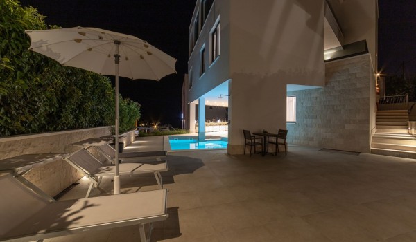 Night view of a private pool and deck chairs on the terrace in a Croatia luxury sea view villa with gym and sauna in Trogir