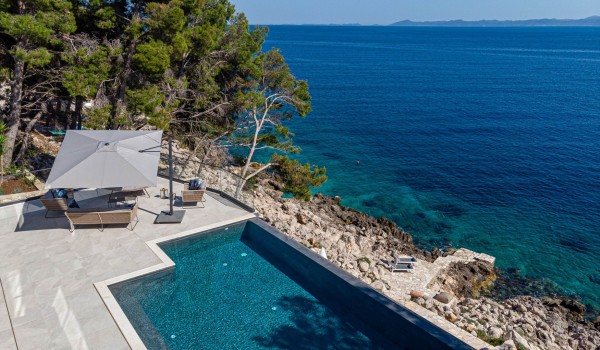 A private sun deck with an infinity pool by the sea in front of the luxury holiday villa Korcula Miracul with a private access to the beach