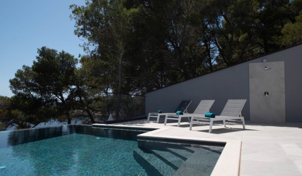 A private sun deck with loungers and an outdoor shower by the infinity pool by the sea in front of the luxury holiday villa Korcula Miracul with private access to the beach