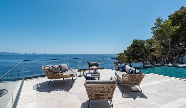 Sun deck with comfortable lounge furniture by the infinity pool in front of the private holiday villa Korcula Miracul with a concierge service