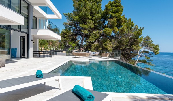 A private sun deck with loungers and lounge area by the infinity pool in front of the luxury seafront villa Korcula Miracul with a private gym on Korcula
