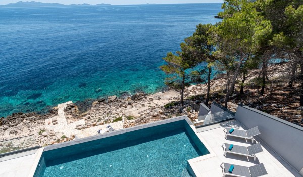 Beachfront sun deck with loungers by the infinity pool in front of the luxury villa Korcula Miracul by the sea with a private gym in Prizba