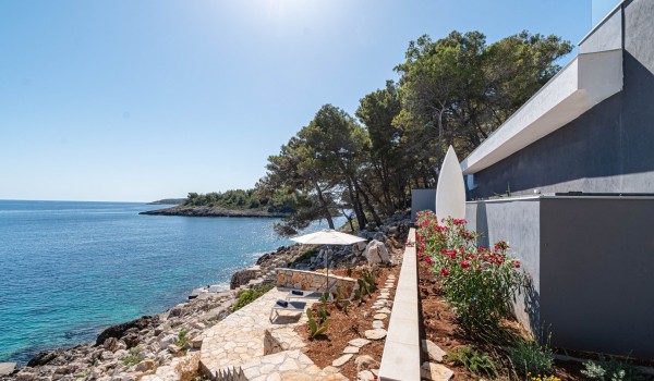 Sunbathing plateau surrounded by stone walls and landscaped cascade garden with stairs leading to the sea in front of the beachfront exclusive villa Miracul Korcula