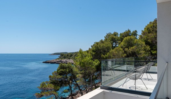 Balcony surrounded with glass panels with coffee table, two chairs and sea view on the first floor of the luxury villa for rent and vacation on Korcula