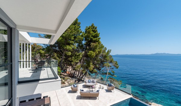 A view on the seafront terrace with a lounge zone and a sea-view by the infinity pool in front of the luxury 6-bedroom villa for family vacations on Korcula