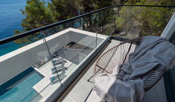 A view on the comfy seating on a balcony and a pool patio by the infinity pool in front of the luxury villa for family vacations on Korcula