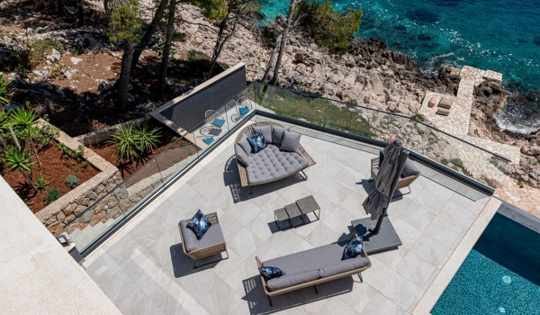 A view on the seafront terrace with a lounge zone and a sea-view by the infinity pool in front of the luxury 6-bedroom villa for family vacations on Korcula