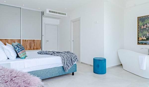 Interior of bedroom with a bathtub, king-size bed and a private balcony in a  luxury villa by the sea for rent on the island of Korcula