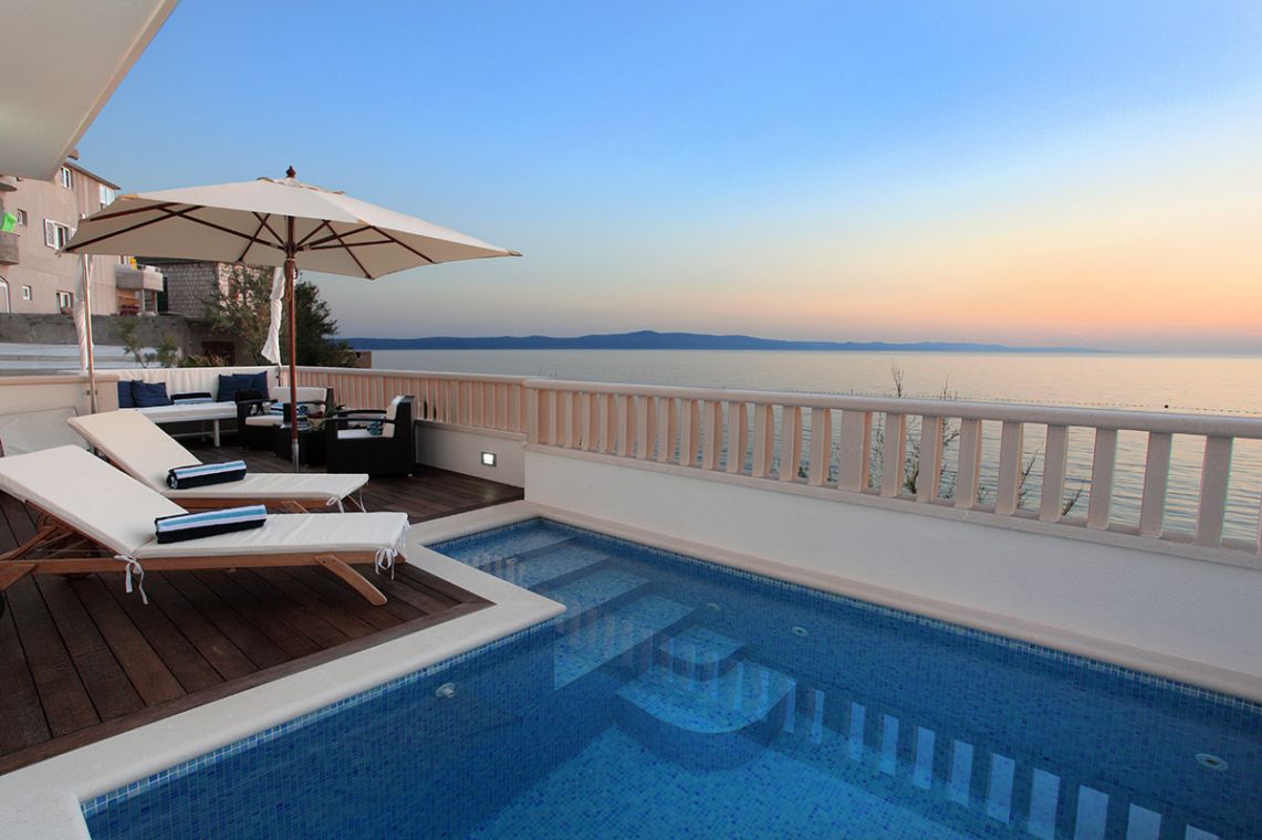 Privater Pool mit Sonnendeck, Liegestühlen und Sonnenschirmen vor der privaten Luxusvilla am Strand in Makarska
