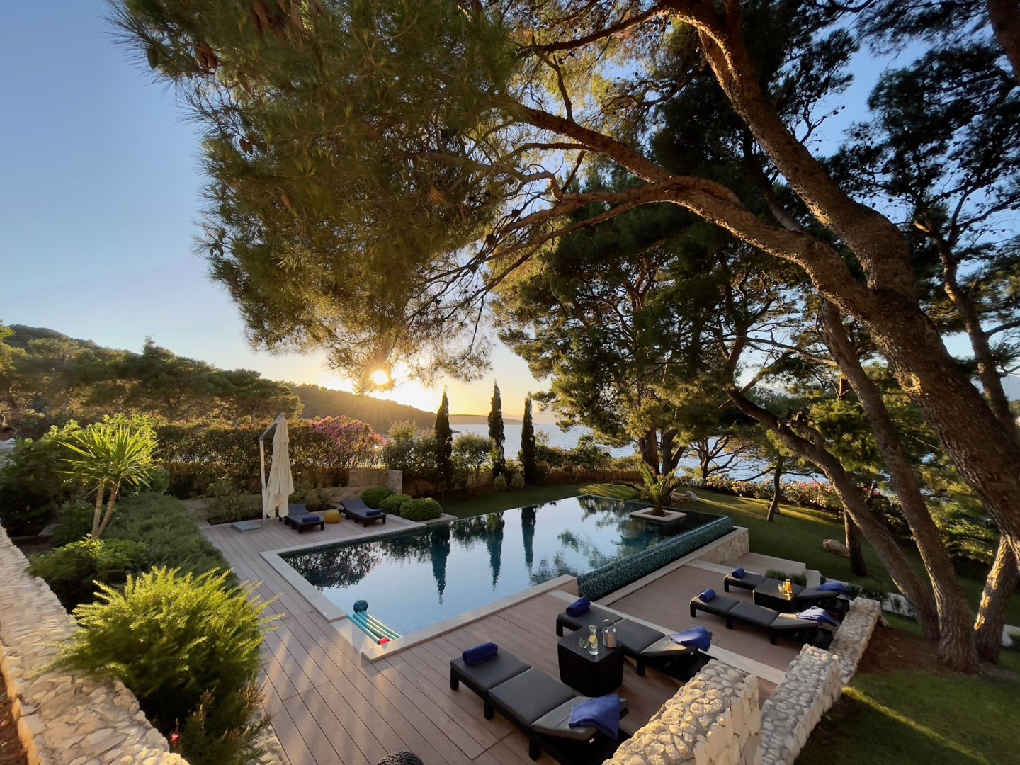 Private heated pool and deck chairs under the trees in a landscaped garden of a Croatia luxury villa Lilly on Brac island