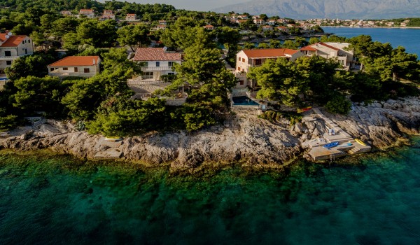 A view of a luxurious holiday villa surrounded by a dense pine forest on Brač