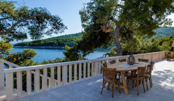 Stone-paved terrace of this holiday villa Brač with dining table and chairs and steps leading to the sea