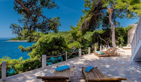 Luxuriously decorated sunbathing area with wooden deckchairs and furniture for relaxing in this luxury villa for rent on the island of Brač