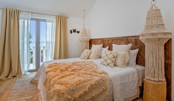 A comfortable bedroom with a king-size bed and access to a balcony in a luxury holiday villa in Sumartin on Brač