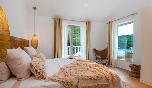 A naturally lit, comfortable bedroom with a king size bed in a modern villa for rent on Brač