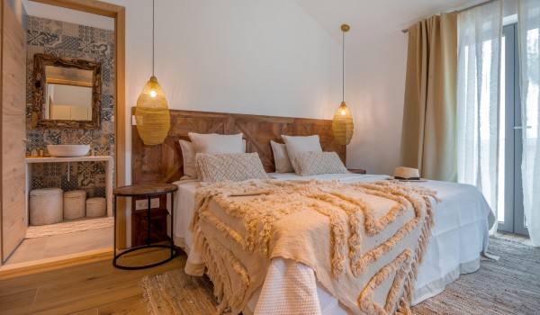 A luxuriously decorated bedroom with an en suite bathroom and a view of the sea and dense pine forest from the modern vacation villa Bliss