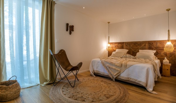 A luxuriously decorated bedroom with an en suite bathroom and a view of the sea and dense pine forest from the modern vacation villa Bliss