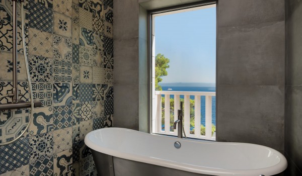 Bathtub and shower in the en suite bathroom with a view of the Mediterranean oasis from the luxurious villa Bliss