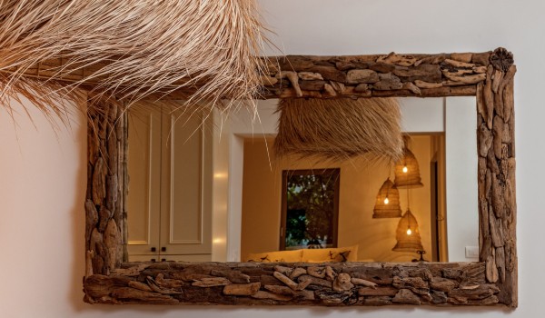 A reflection of the modern details of the holiday villa in a mirror with a wooden frame that exudes rusticity