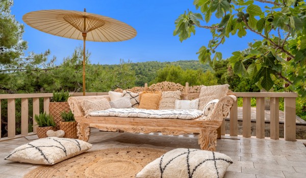 A luxuriously decorated sofa with an airy parasol on the outdoor terrace of the luxury villa Bliss, surrounded by nature