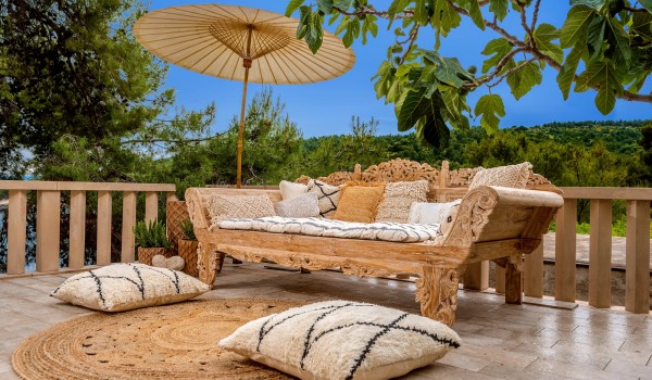 A luxuriously decorated sofa with an airy parasol on the outdoor terrace of the luxury villa Bliss, surrounded by nature