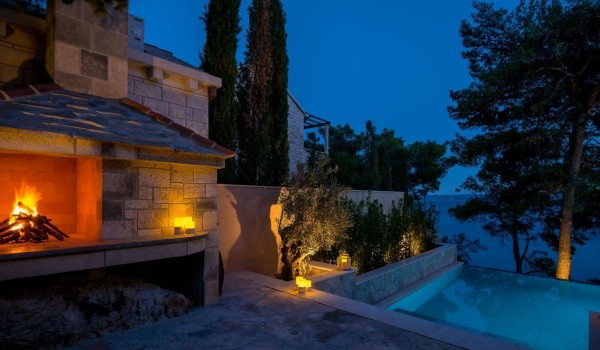 View of the fireplace by the pool in the evening on the property of the luxury villa Brač by the sea
