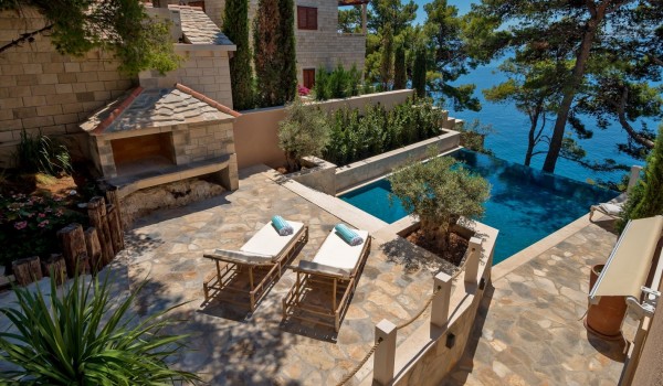 A view of the spacious pool next to which there is a fireplace and two deckchairs on the property of the rental luxury villa  Brač