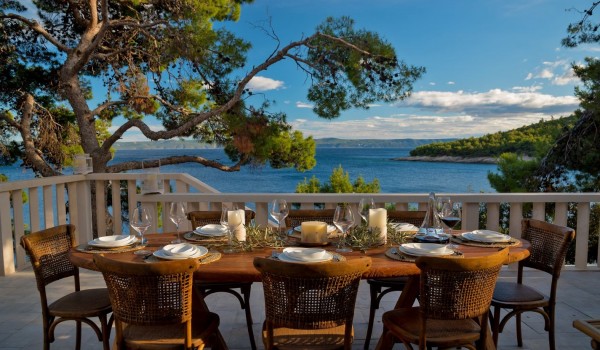 Richly decorated dining table with chairs on the outdoor airy terrace of this rental villa Brač